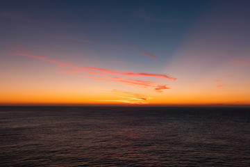 Warm colorful sunrise sky over the ocean horizon.