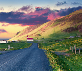 Dramatic summer sunset with Reyniskirkja church, Vik village location. Colorful outdoor scene in...