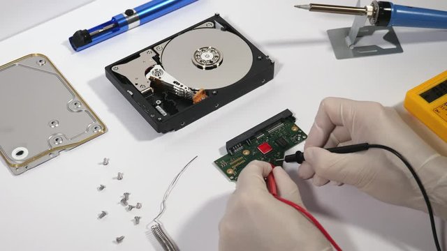 Computer technician repairing broken pc hard disk drive to recover lost data