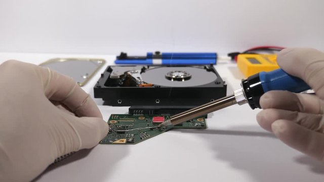 POV electronic technician repairs hard disk drive by soldering parts