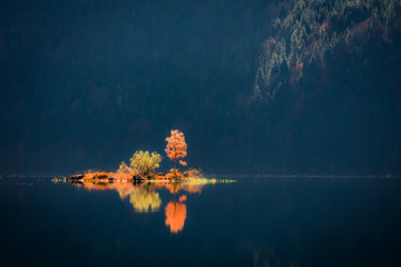 Great autumn scene of Eibsee lake. Unreal morning view of first sunlight glowing small island on...