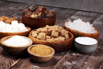 Various types of sugar, brown sugar and white on rustic wooden table