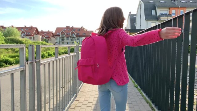 Back view - schoolchild go to school with backpack. Cute child - teen girl with bag Back to school. Concepts of childhood and education.