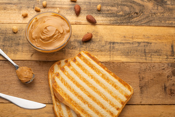 peanut butter, toast and nuts on a wooden texture, top view, breakfast, tasty and hearty food
