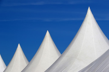 White roofs of tents aligned over blue sky