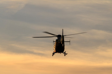 Naklejka na ściany i meble Silhoutte of a flying helicopter in backlight of dusk in Vienna, Austria