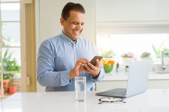 Middle Age Man Working With Laptop And Using Smartphone