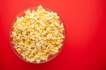 plate with popcorn on a red background. layout. top view. concept of cinema, viewing, rest