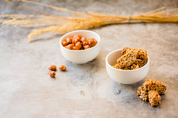 Gozinaki bars (Georgian Christmas confection) made of sunflower seeds and honey. Peanuts in sugar in white bowl and on gray background.Healthy sweet dessert snack concept.