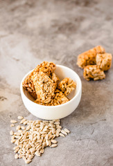 Gozinaki bar of seeds on a gray background. Delicious oriental sweets from the seeds of sunflower, sesame covered with honey with shiny glaze. Macro Country Style.Selective focus. Copy space for text.