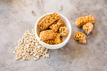 Gozinaki bar of seeds on a gray background. Oriental sweets from the seeds of sunflower, sesame covered with honey with shiny glaze. Macro Country Style. Dessert snack concept.