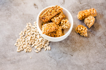 Gozinaki bar of seeds on a grey background. Sweets from the seeds of sunflower, sesame covered with honey with shiny glaze. Macro Country Style.Top view. Copy space for text