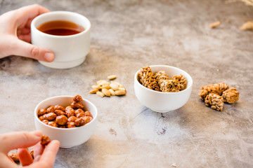 Dessert bars made of sunflower seeds  in a honey caramel. Gozinaki - traditional Georgian confection. Caramelized peanuts in white bowl and on gray background.. In the hands of a young woman.