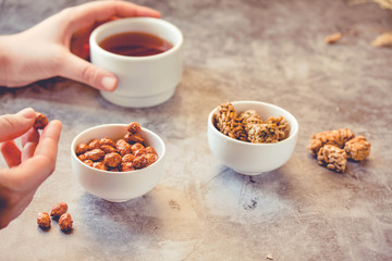Dessert bars made of sunflower seeds  in a honey caramel. Gozinak, Caramelized peanuts in white bowl and on gray background..The process of eating. In the hands of a young woman. Toning.