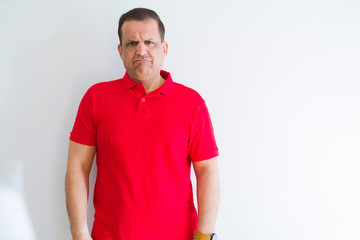 Fototapeta premium Middle age man wearing red t-shirt over white wall depressed and worry for distress, crying angry and afraid. Sad expression.