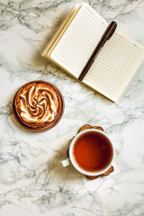 Blank note book, a cup of tea and cake. Top view with copy space. Work place. Planing concept.