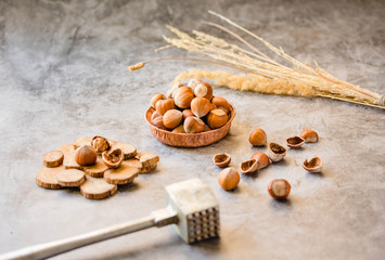 Hazelnuts in the shell in a small bowl and nutcracker. On a gray background.