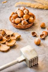 Hazelnuts in the shell in a small bowl and nutcracker. On a gray background.