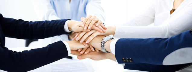 Business team showing unity with their hands together. Group of people joining hands and...