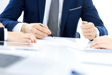 Group of business people and lawyers discussing contract papers sitting at the table, close-up. Successful teamwork, cooperation and agreement concepts