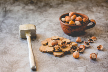 Hazelnuts in the shell in a small bowl and nutcracker. On a gray background.Tone.
