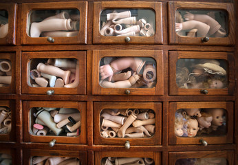 Parts of dolls inside small boxes for broken toys. Details of children games