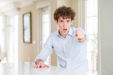 Fototapeta premium Young business man with curly read head pointing displeased and frustrated to the camera, angry and furious with you