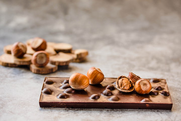 Dark chocolate with hazelnuts in the shel on gray backgroundl, closeup.
