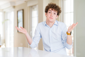 Fototapeta premium Young business man with curly read head clueless and confused expression with arms and hands raised. Doubt concept.