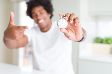 African American man holding stopwatch very happy pointing with hand and finger