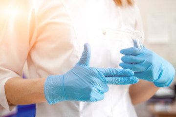 Professional medical physician gynecologist doctor in white uniformin blue gloves makes gynecological finger sign. Cabinet with medical equipment on background. Woman health and pregnancy concept