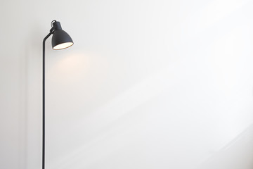 Standing black lamp over white wall