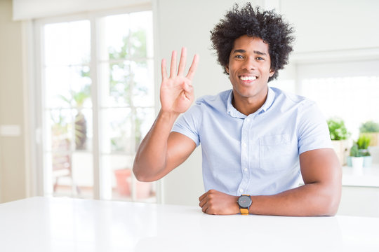 African American business man showing and pointing up with fingers number four while smiling confident and happy.