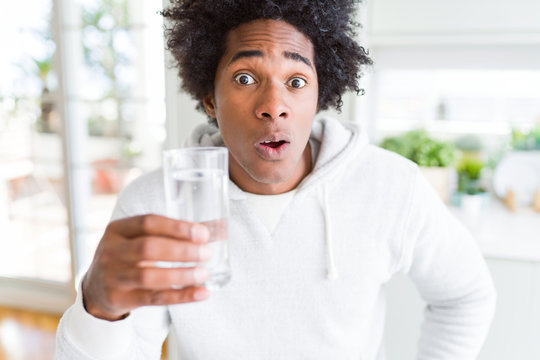 African American man drinking a glass of water at home scared in shock with a surprise face, afraid and excited with fear expression