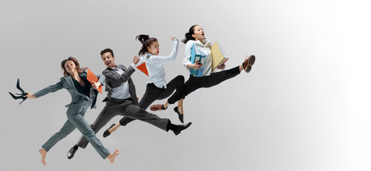 Fototapeta na wymiar Happy office workers jumping and dancing in casual clothes or suit with folders isolated on studio background. Business, start-up, working open-space, motion and action concept. Creative collage.