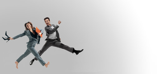 Naklejka na ściany i meble Happy office workers jumping and dancing in casual clothes or suit with folders isolated on studio background. Business, start-up, working open-space, motion and action concept. Creative collage.