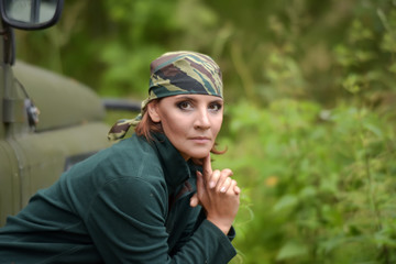 Woman wearing camouflage bandana against the backdrop of UAZ. - 270370134
