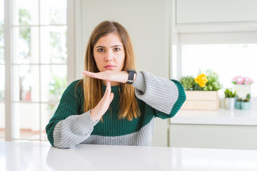 Young beautiful plus size woman wearing casual striped sweater Doing time out gesture with hands,...