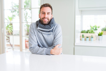 Handsome man wearing casual sweatshirt at home and smiling positive