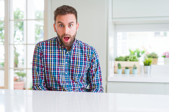 Handsome man wearing colorful shirt afraid and shocked with surprise expression, fear and excited face.