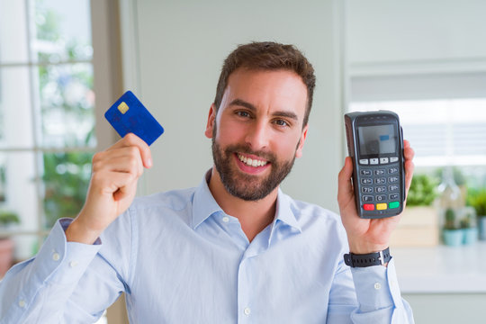 Handsome business man holding pos terminal and credit card, buying and payment using dataphone