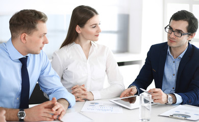 Group of business people discussing questions at meeting in modern office. Managers at negotiation or brainstorm. Teamwork, partnership and business concept