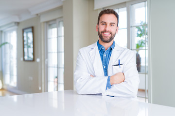 Fototapeta premium Handsome doctor man wearing medical coat at the clinic happy face smiling with crossed arms looking at the camera. Positive person.