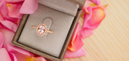 elegant wedding diamond ring in jewelry box on beautiful pink rose petal background close up