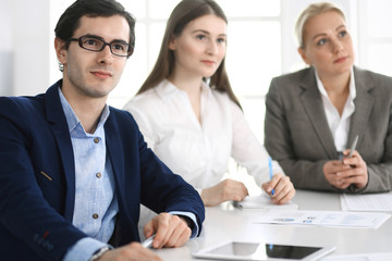 Fototapeta premium Group of business people discussing questions at meeting in modern office. Managers at negotiation or brainstorm. Teamwork, partnership and business concept