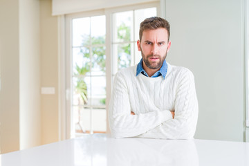 Fototapeta premium Handsome man wearing casual sweater skeptic and nervous, disapproving expression on face with crossed arms. Negative person.