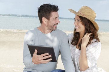 young couple using a digital tablet at seaside town