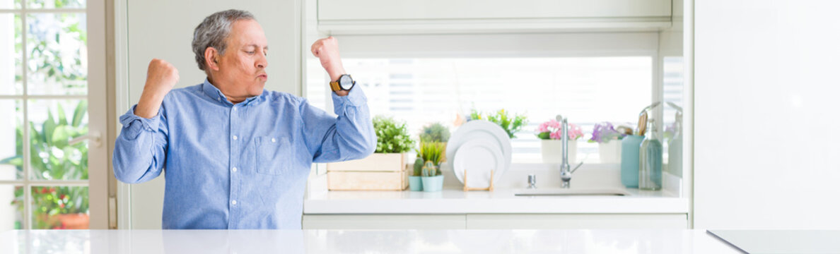 Wide Angle Perspective Of Handsome Senior Man At Home Showing Arms Muscles Smiling Proud. Fitness Concept.