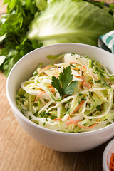 Coleslaw salad in white bowl on wooden table