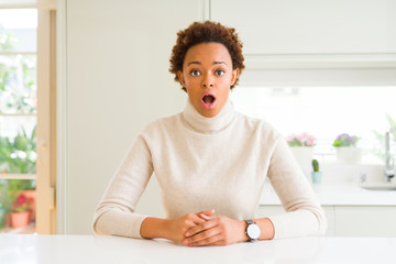 Young beautiful african american woman at home afraid and shocked with surprise expression, fear...